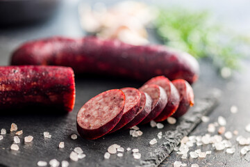 Sliced smoked pork sausage on black table.