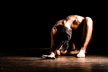 Bailarin profesional performando y simulando desnudez entre sombras