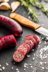 Sliced smoked pork sausage on black table.