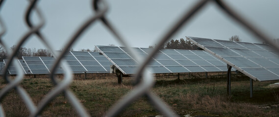 solar panels on a field behind a fence on a moody winter day