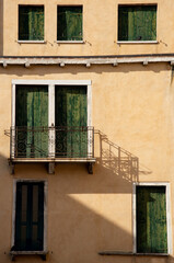 Fototapeta na wymiar Hotel rooms with green wooden closed doors and vintage balcony. Venice Italy