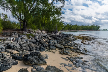 Fototapeta na wymiar A view of rocks and boulders on the shoreline of a deserted bay on the island of Eleuthera, Bahamas on a bright sunny day