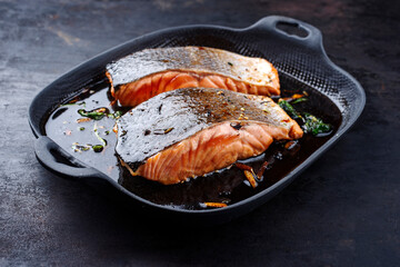 Traditional Japanese salmon fish teriyaki filet with soy souce and spinach as close-up in a Nordic...