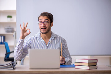 Young male teacher sitting in the classroom