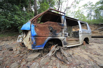An abandoned burnt out car wreck with bullet holes