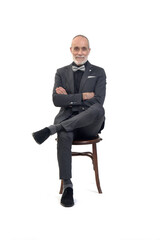 front view of a man sitting  on chair with suit and tie and cross legged and arms crossed on white background