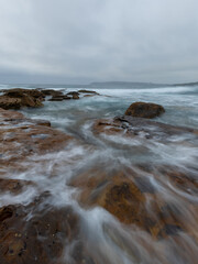 Wave water flowing on the rocky coastline.