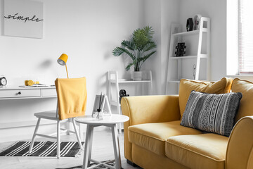 Interior of living room with yellow sofa, workplace and houseplant