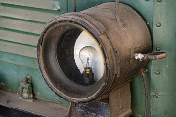 very old headlight on a locomotive with bulb without glass very rusty