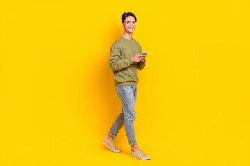 Fototapeta na wymiar Full size profile photo of cheerful person hold smart phone walking isolated on yellow color background