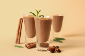 Shots of delicious chocolate pudding with mint, anise and cinnamon on beige background, closeup