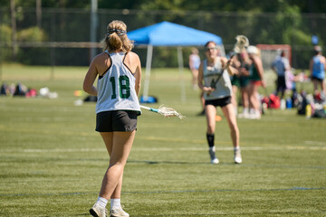 THE WOODLANDS, TEXAS - OCTOBER 2022: The Woodlands High School varsity lacrosse team is playing in a  tournament at  Alden Bridge Sports Park. The teenage girls are wearing white and green uniforms