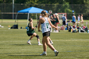 THE WOODLANDS, TEXAS - OCTOBER 2022: The Woodlands High School varsity lacrosse team is playing in a  tournament at  Alden Bridge Sports Park. The teenage girls are wearing white and green uniforms