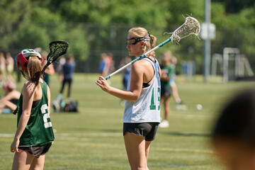 THE WOODLANDS, TEXAS - OCTOBER 2022: The Woodlands High School varsity lacrosse team is playing in a  tournament at  Alden Bridge Sports Park. The teenage girls are wearing white and green uniforms