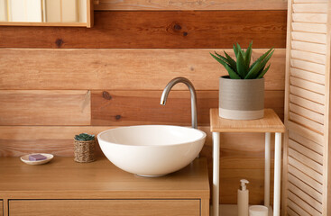Fototapeta na wymiar Ceramic sink on table near wooden wall in bathroom