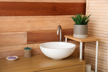 Ceramic sink on table near wooden wall in bathroom