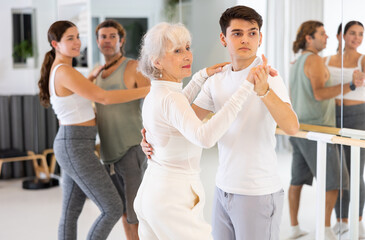 Cheerful adult men and women of different ages training in dance modern studio.