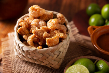 Chicharrones. Deep fried pork rinds, crispy pork skin pieces, traditional mexican ingredient or snack served with lemon juice and red hot chili sauce.