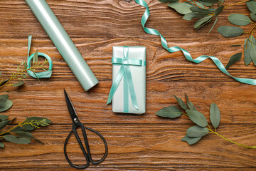 Composition with gift box, wrapping paper, ribbon, scissors and eucalyptus branches on wooden background. Women's Day celebration