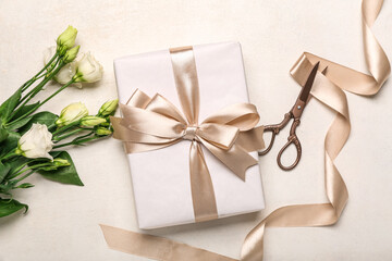 Gift box, beautiful eustoma flowers and scissors on light background. Women's Day celebration