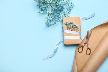 Gift box, gypsophila flowers, wrapping paper and scissors on color background. Women's Day...