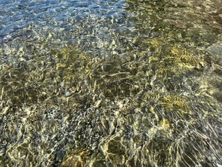 Sea pebbles and stones at the bottom in clear water.