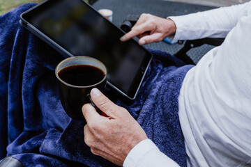hands of Hispanic man reading a book in the morning and holding coffee cup sitting down on the terrace of a country house in Mexico Latin America
