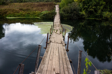 Warped and lying on the water footbridge across the river