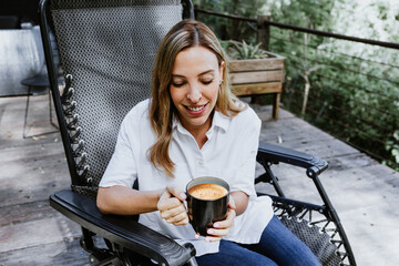 Hispanic woman drinking and holding coffee or tea cup on the terrace of a country house in Mexico Latin America