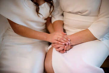 Bride on wedding day holding her mother's hands. Concept of relationship between moms and daughters - 566411071
