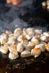 A closeup view of chopped chicken breast on the griddle.