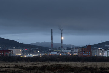 Evening urban industrial landscape. View of the city and the pipes of the thermal power plant....