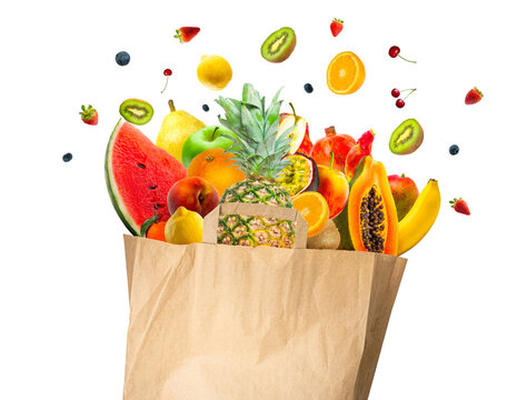 Explosion of Healthy food in the recycle ecological paper bag. Studio shot of different types of fruits isolated on transparent background. Concept healthy food