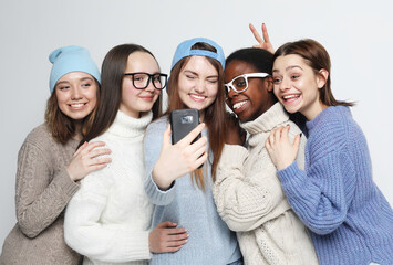 African-american and caucasian teenage friends company make selfie over white grey background.