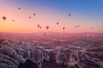 Amazing sunrise Cappadocia with set colorful hot air balloons fly in pink sky with first sun light....