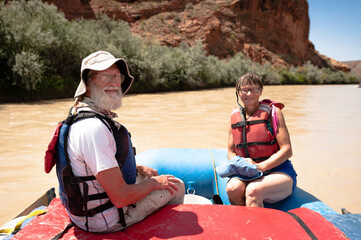 Portrait of senior man and woman sitting in inflatable raft on San Juan River
