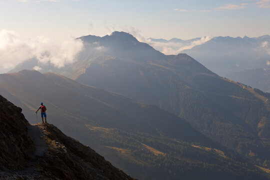 A male hiker enjoys the beautiful view over mountains and valleys, during the Glocknerrunde, a 7 stage trekking from Kaprun to Kals around the Grossglockner, the highest mountain o