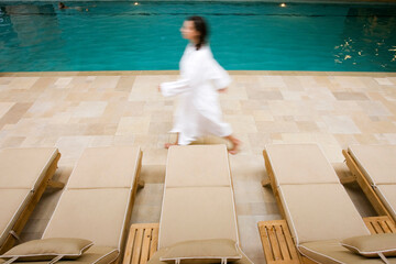 Woman in a white robe walking by the indoor pool at a spa, Stowe VT.
