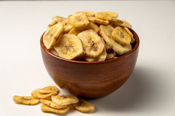 Dried banana chips in a bowl isolated on white.