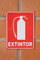 red extinguisher sign on brick wall in spanish