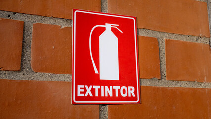 red extinguisher sign on brick wall in spanish