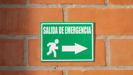 Green emergency exit sign in Spanish