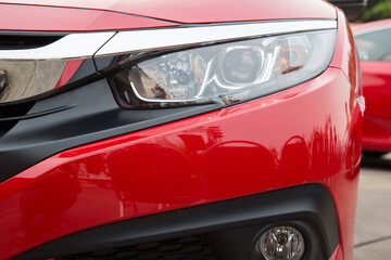 redatory car headlight and hood of powerful sports car with matte red.