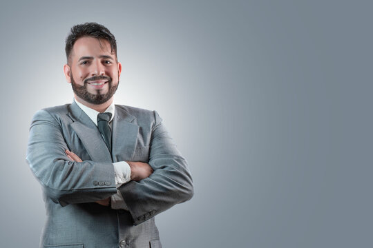 Empresario trajeado con los brazos cruzados sobre un fondo gris