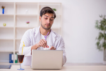 Young male chemist examining soft drink