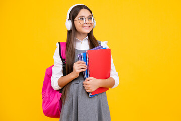 School girl, teenage student in headphones and books on isolated studio background. School kids with backpack. Happy face, positive and smiling emotions of teenager girl.