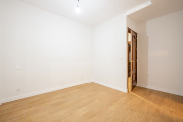 Empty bedroom with varnished sapele wood doors, laminated flooring and white walls