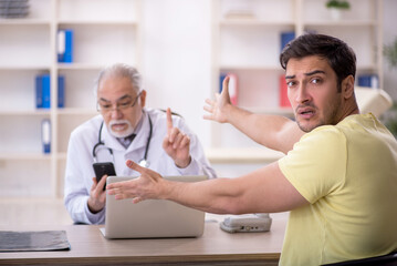Obraz premium Young male patient visiting old male doctor