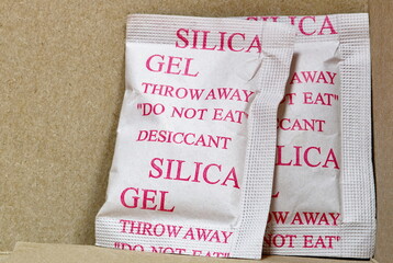 Two Silica gel packets in box porous desiccant substance packing absorb humidity moisture.