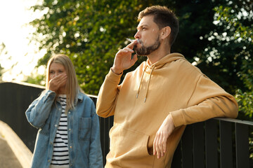 Handsome man smoking cigarette at public place outdoors